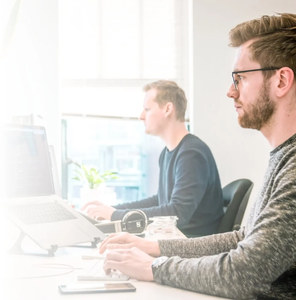 Two men sit in front of computers